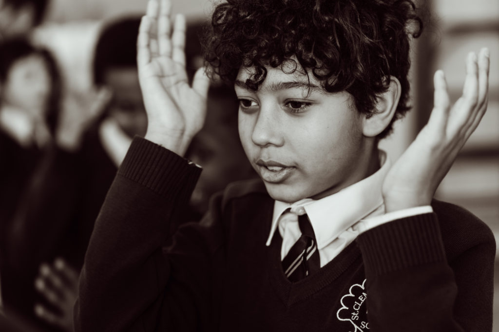 Close up, black and white, KS2 primary pupil, boy, holding hands up to the sides of his head, mouth open.