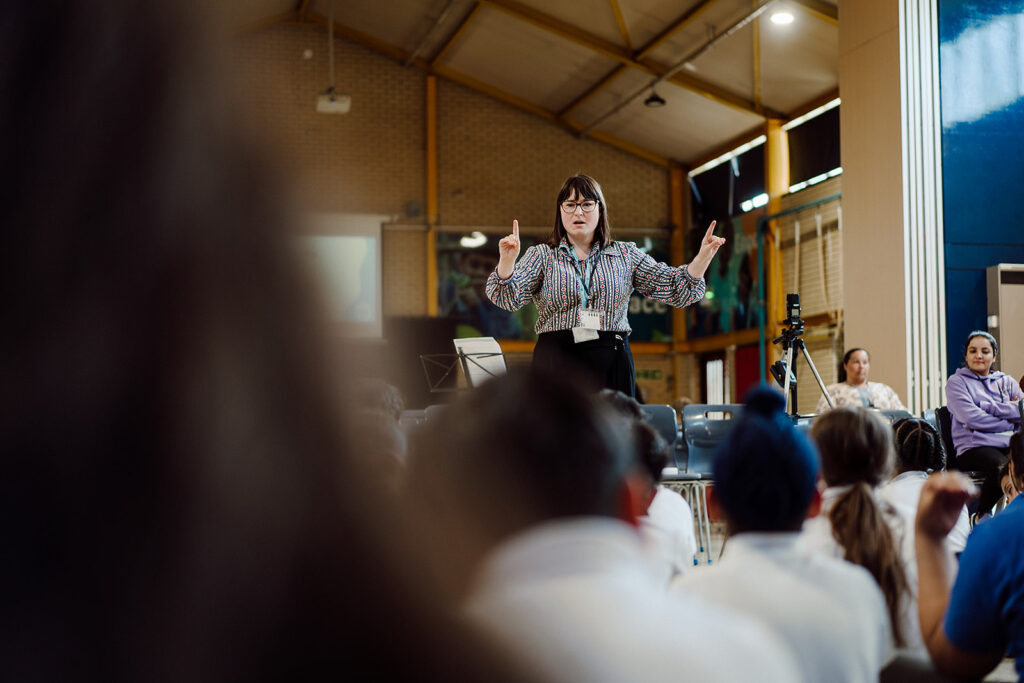 A female music teacher is conducting a primary school choir